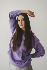 Portrait of young woman with long straight hair dressed in purple hoodie. Sport outfit