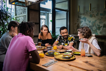 Young multi-ethnic friends celebrating something in a cafe.