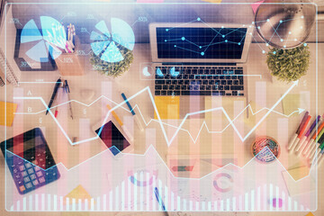 Double exposure of forex chart drawing over table background with computer. Concept of financial research and analysis. Top view.