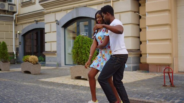 Charming african man and woman dancing on street. Sweet couple dancing in city
