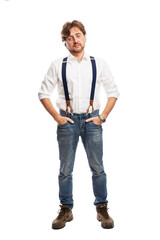A man with red hair in a white shirt and jeans with suspenders stands. Full height. Isolated on a white background. Vertical.