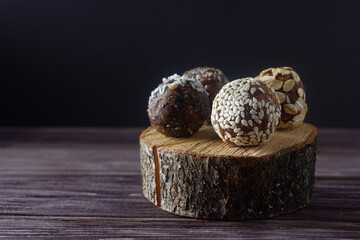 Raw vegan dessert energy balls or raw vegan candy with nuts and dried fruits on wooden background. Sugar free.
