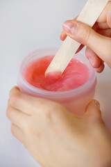 Paraffin therapy. Hand skin care using cosmetic paraffin. girl with a stick takes paraffin from a...