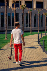 Leisure. An attractive guy rides a skateboard in the park.