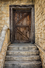 Fototapeta na wymiar Door entrance with ancient European style. It consists of wooden door, stone wall and stairs.