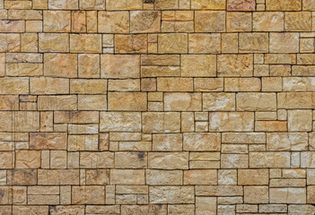 Pattern and texture of rectangular yellow dry stone block wall. It was constructed from stones without any mortar to bind them together.
