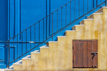 External stairway of vintage blue building. Staircase consists of metal handrails, marble steps treads and under stairs storage.