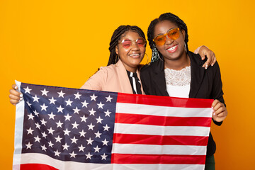 two beautiful african women with american flag on yellow background