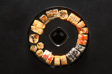 Sushi set as Christmas wreath served with soy sauce on black background. View from above.