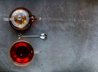 A Cup of tea, a teapot, a dessert spoon on a dark background in a minimalistic style. Creative.
