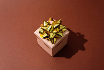 Beige Gift box with golden bow on brown