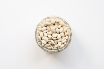 glass jar with white bean. navy, cannellini, white kidney bean on white beige background top view photo 