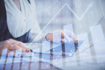 Double exposure of businesswoman hands typing on computer and forex graph hologram drawing. Financial analysis concept.
