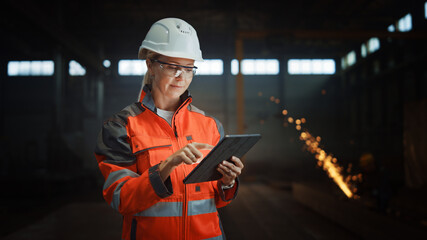 Professional Heavy Industry Engineer/Worker Wearing Safety Uniform and Hard Hat Uses Tablet...