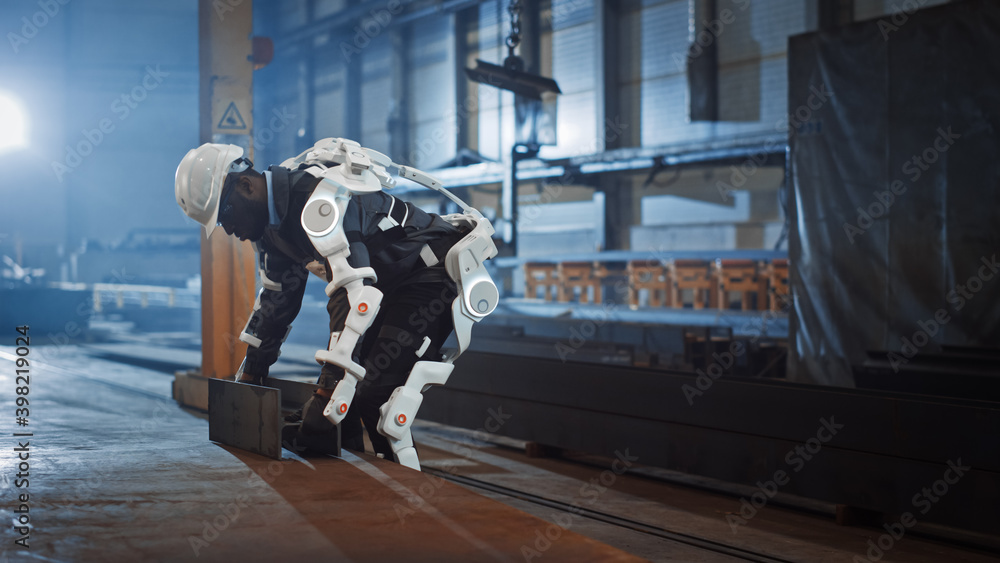 Poster black african american engineer is testing a futuristic bionic exoskeleton and picking up metal obje