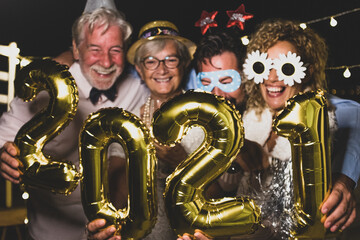 group of four people enjoying new year night celebrating with sparklers in the middle and looking at the camera - adults having fun together