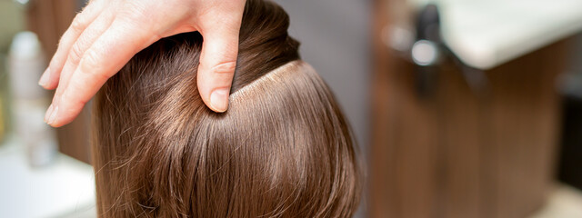 Fototapeta premium Hairdresser checks short brown hairstyle of a young woman in a beauty salon