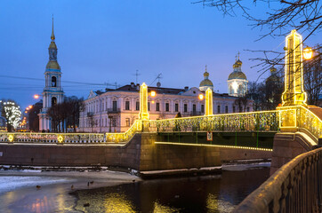 Fototapeta premium Saint Petersburg in Christmas holidays. People take pictures on mobile phones of festively decorated bridges in the place of Seven Bridges in the New Year's lighting. Festive cityscape