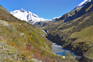 Naklejka na ściany i meble river in alpine valley crossing mountain with a glacier background