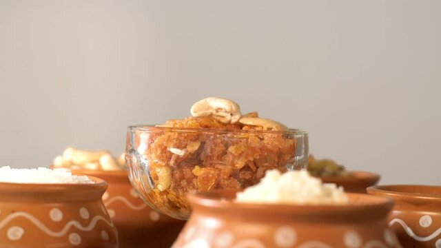 A beautiful decorative bowl of Gajar Ka Halwa/carrot pudding kept with its ingredients. Popular Indian sweet dish Gajar Ka Halwa prepared with grated carrot  Khoa  milk  sugar  Desi ghee  and dry f...