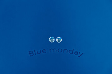 Sad eyes and an inscription in the form of a sad emoticon. Blue Monday text  on a blue background with copy space. Blue Monday concept. 