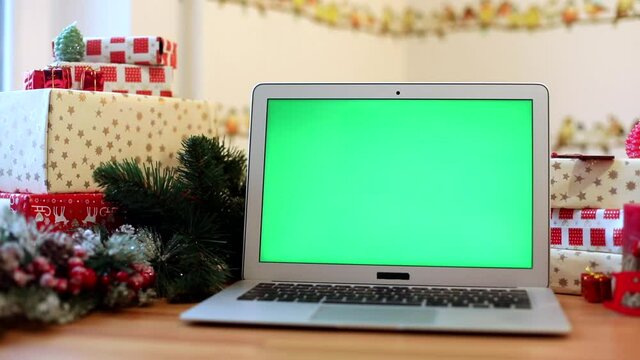 Green screen laptop with Christmas decoration on background. Presents for friends. Chromakey notebook. Free content. mockup monitor. Online greeting. Internet surfing. Celebrating concept.