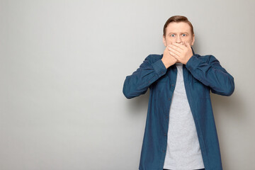 Portrait of shocked overwhelmed man covering mouth with hands