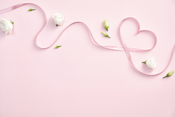 Valentines day concept. Heart shaped ribbon and roses flowers on pastel pink background. Flat lay,...