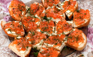 Sandwiches of white bread, butter, salted fish and dill on a plate against the tablecloth