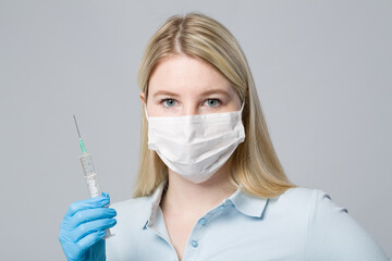 female doctor or nurse with medical face mask and medical gloves with a pulled up syringe ready for vaccination 