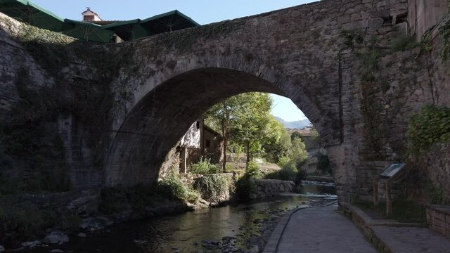 Potes, Spain - September 2, 2020: DOLLY SHOT - Puente de la Carcel bridge. This bridge is known as the Jail Bridge. It is located on the Quiviesa river next to the Torre del Infantado.