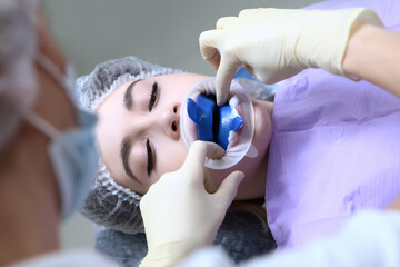 The dentist conducts professional oral hygiene for a young girl. Caries prevention. A young girl at...