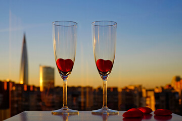 Couple glasses of champagne and red marmalade hearts on city view and blue sky background in Saint-Petersburg, Russia, Lahta center building. Copy space, selective focus