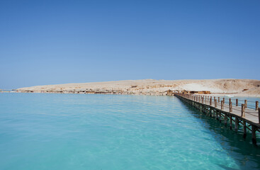 Fototapeta na wymiar A bridge leading to a sandy island. Around the blue sea water. Summer. Heat. Egypt.
