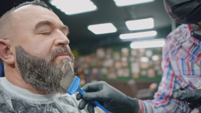 A barber paints a mustache and beard of client man