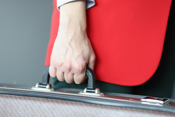 Woman in red jacket holding suitcase close-up
