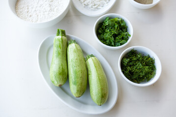 Baby zucchini on a white plate background. over white wooden table.  Organic food.