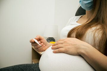 The pregnant woman is checking the temperature by digital thermometer