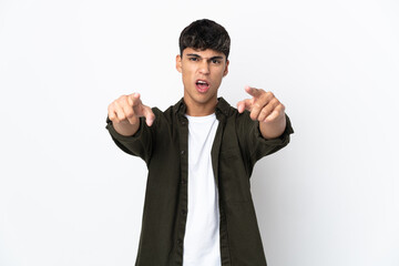 Young man over isolated white background surprised and pointing front