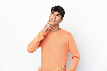 Fototapeta premium Young man over isolated white background thinking an idea while looking up