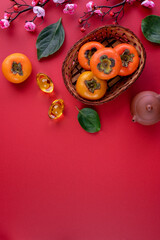 Top view of fresh sweet persimmons with leaves on red table background for Chinese lunar new year
