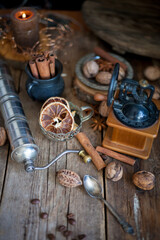 Cinnamon sticks, dried orange, star anise, aromatic spices on a wooden table. Christmas lights garlands. New Year's still life. Manual coffee grinder and beans. Food on the table.
