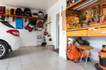 Home suburban car garage interior with wooden shelf, tools equipment stuff storage warehouse on white wall indoor. Vehicle parked at house parking background. DIY workbench for repair home appliances - obrazy, fototapety, plakaty