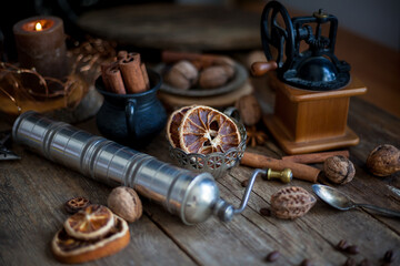Cinnamon sticks, dried orange, star anise, aromatic spices on a wooden table. Christmas lights garlands. New Year's still life. Manual coffee grinder and beans. Food on the table.