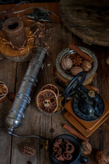 Cinnamon sticks, dried orange, star anise, aromatic spices on a wooden table. Christmas lights garlands. New Year's still life. Manual coffee grinder and beans. Food on the table.
