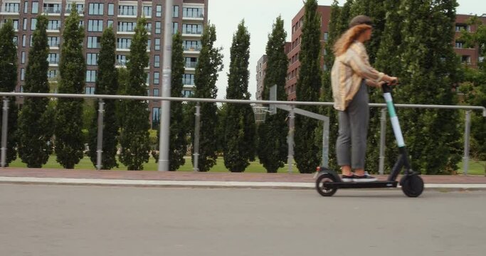 girl rides an electric scooter or e-scooter roller in hamburg city germany, ecological e mobility in the urban city, 4k Steady Parallel Side Shot, modern transportation
