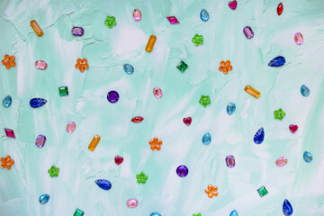 Trendy plastic colorful crystal rhinestone for sewing on green abstract background. Diy clothing decoration and hobby market concept, copy space