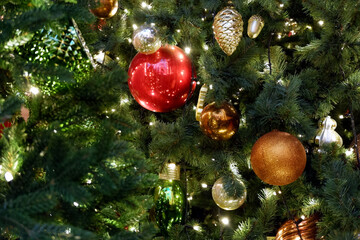Obraz na płótnie Canvas Reg, gold, green and silver christmas decorations on a christmas tree with lights close up view