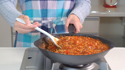 キッチンでミートソースを作る女性