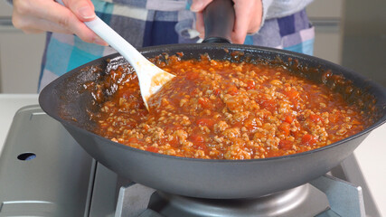 キッチンでミートソースを作る女性